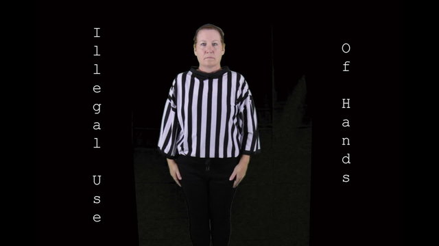 Woman dressed as a football referee signaling Illegal Use of Hands.