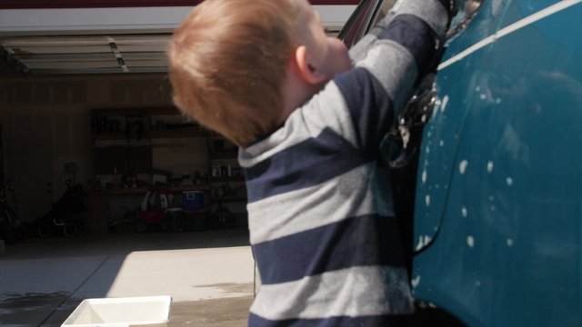 Mother washing car with her toddler