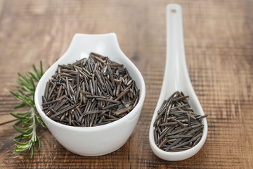 Kanadischer Wildreis in Porzelanschale auf Holzbrett