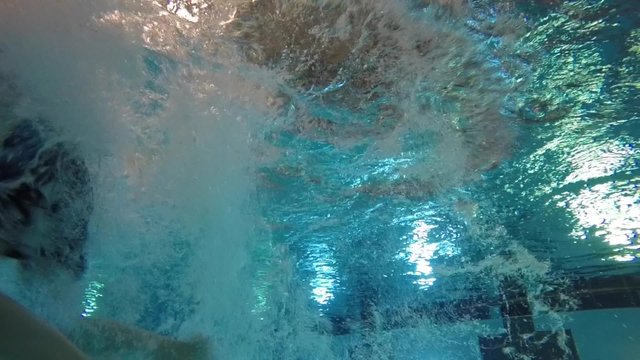 Slow motion of a child jumping into pool underwater shot