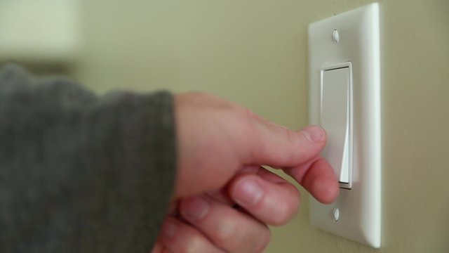 a hand turning on a light switch
