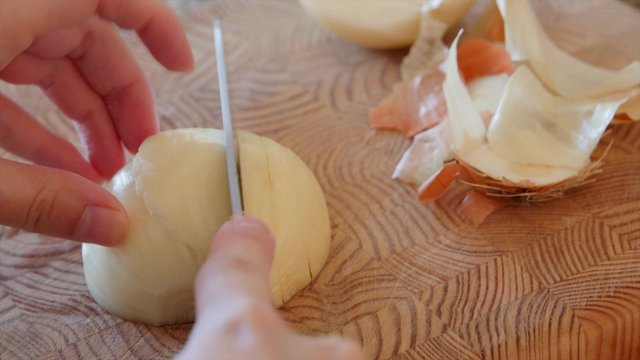 A woman slices an onion on a cutting board