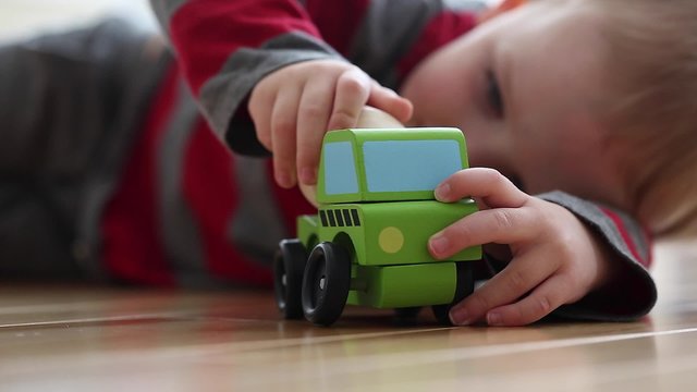 a little boy plays with toy truck