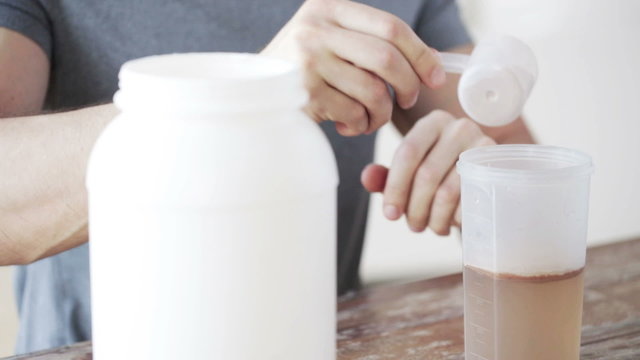 close up of man with protein shake bottle and jar