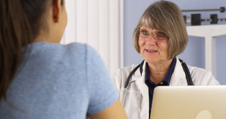 Obraz premium Mature doctor consulting Hispanic woman patient