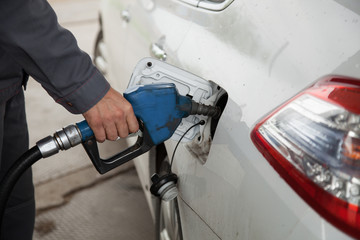 Male hand pumping petrol into car, refueling with nozzle at gas