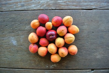 Pile of ripe juicy orange and red apricots on the brown rustic wooden table; rural vintage concept. Shot from above. Concept of organic farming; fresh, natural, unprocessed fruit.