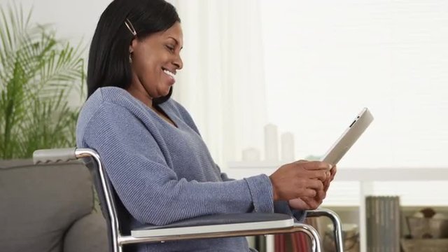 Smiling disabled senior woman using tablet computer in chair