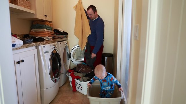 father doing the laundry with his toddler boy