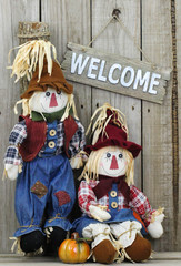 Welcome sign hanging by two scarecrows