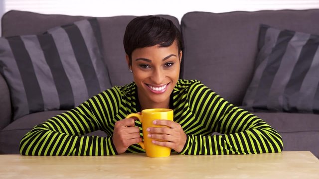 Black woman smiling at coffee table with mug
