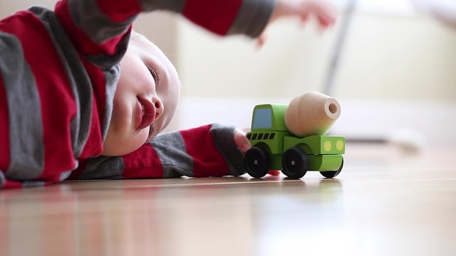 a little boy plays with toy wood truck