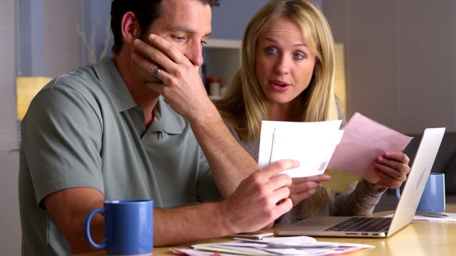 Angry couple fighting with bills