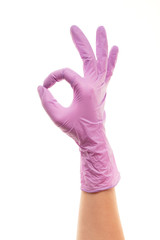 Female doctor's hand in purple surgical glove showing OK sign