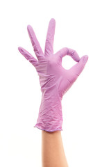 Female doctor's hand in purple surgical glove showing OK sign