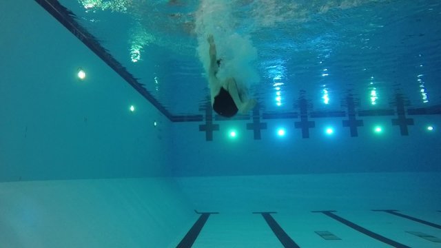Slow motion of swimmer cannon ball into pool underwater side shot