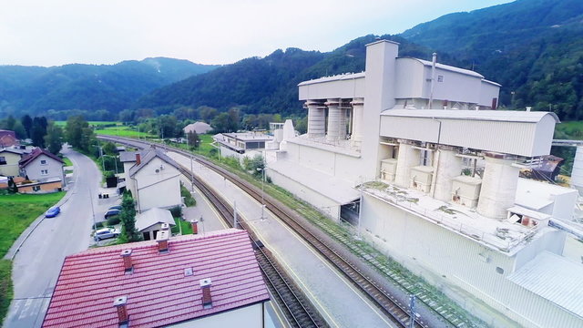 Small train station and industrial factory next to it aerial shot