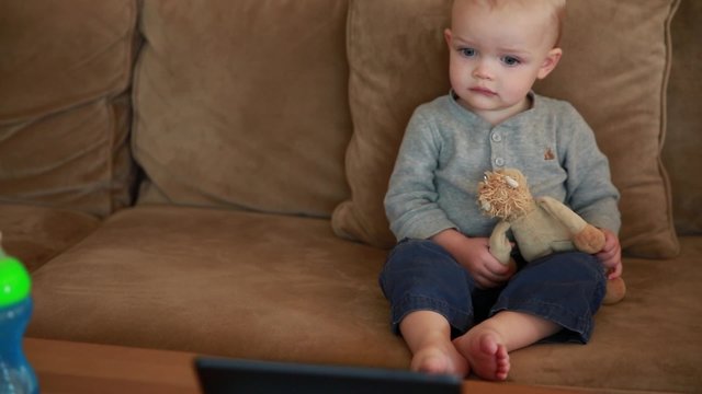 cute toddler boy watching a movie on a tablet