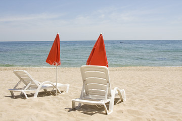 Red beach umbrellas and chaise longue on beach