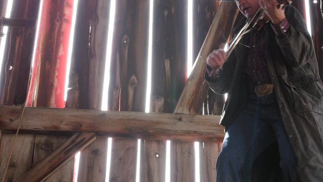 A cowboy plays an old fiddle in barn rafters for the barn dance