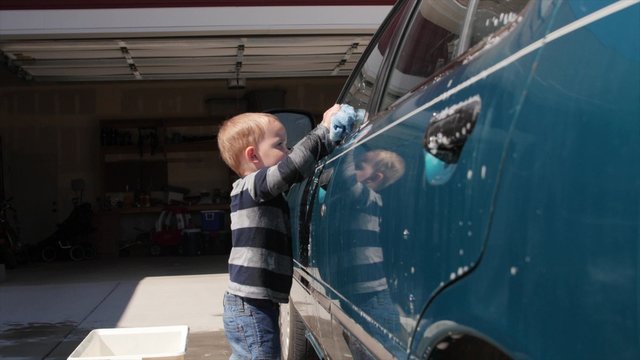 A mother washing car with her toddler