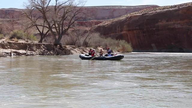 a family rowing down a desert canyon river in rafts