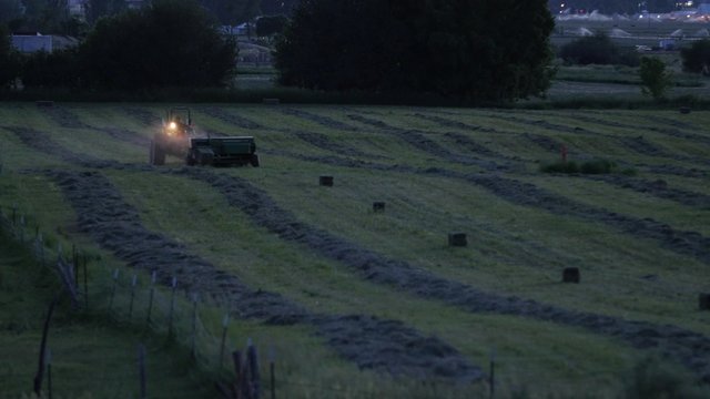 A farmer bailing hay at night
