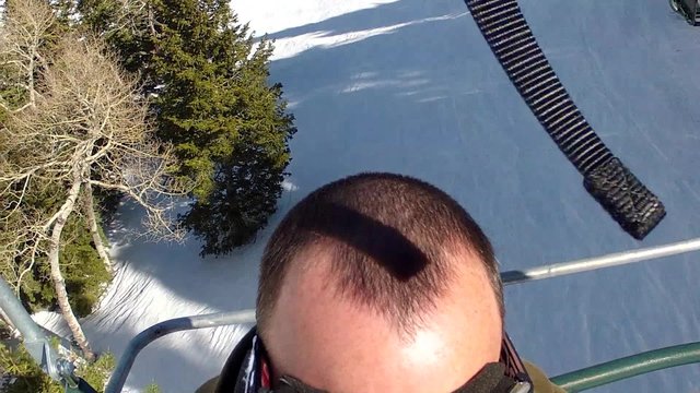 man riding up ski lift in spring