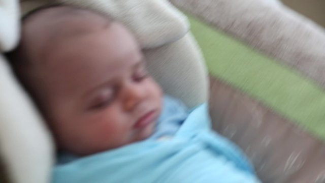 newborn baby boy in the swing at home