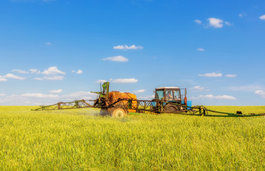 Fototapeta premium Farming tractor spraying green field