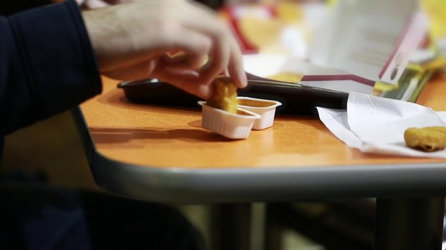man dips chicken nuggets in the bbq sauce