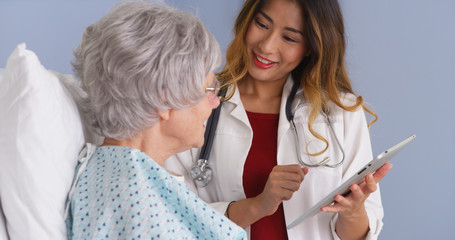 Japanese physician using tablet talking with mature woman patient