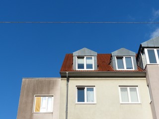 Altbau mit Mansarden und Dachgauben in Beige und Naturfarben vor strahlend blauem Himmel im...
