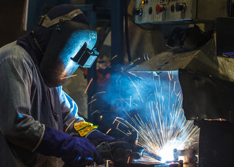 worker welding in production line
