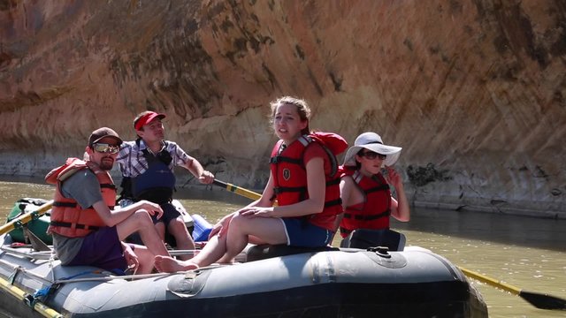 families rowing river rafts on san juan river by cliff