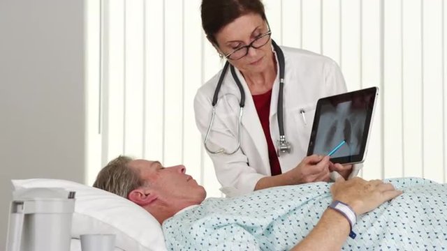 Senior doctor talking to elderly patient lying in bed