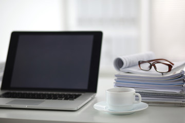 Obraz na płótnie Canvas newspaper,eyeglasses, cup and laptop