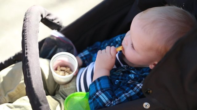 a baby in stroller eating lunch