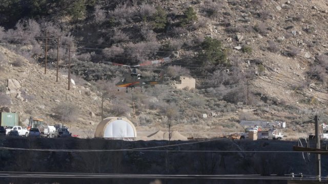 Helicopter carrying supplies hovers above ground