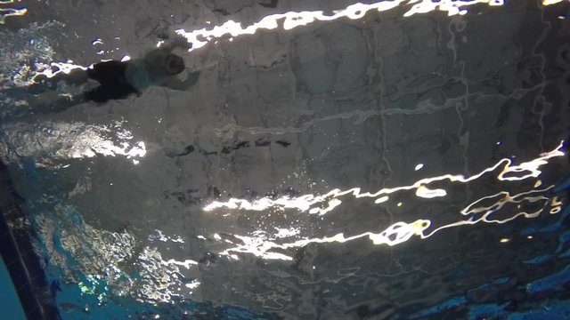 Slow motion of man diving into a pool underwater shot
