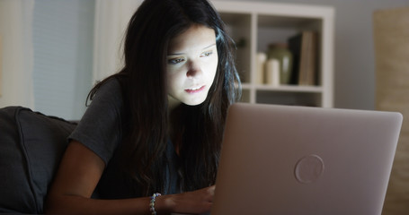 College student staying up late writing her paper on laptop