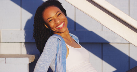 Happy black woman sitting on outdoor stairs laughing
