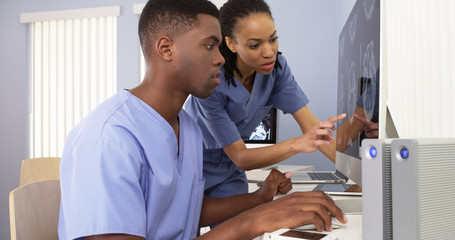 Two African American medical specialists working together on computer