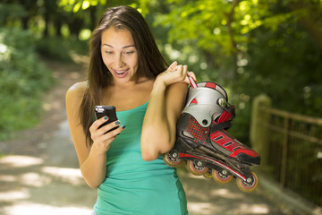surprised woman with inline skates reading news on mobile phone