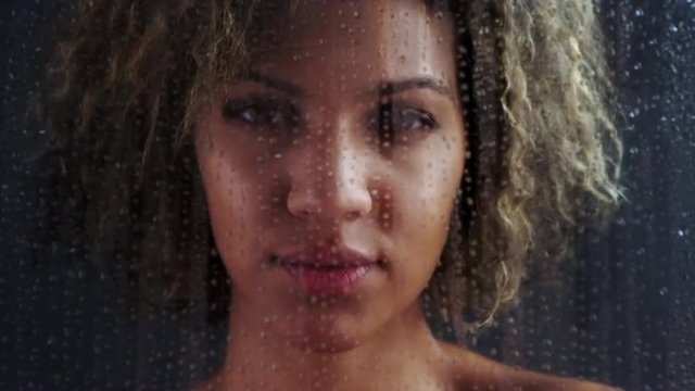 Portrait of African woman looking through foggy glass