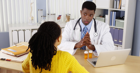 African American patient talking to African American doctor at office desk