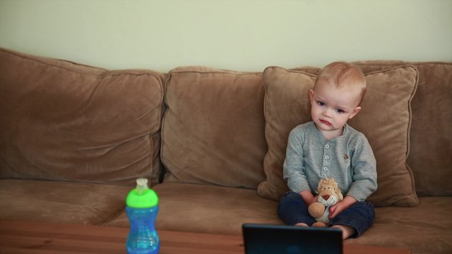 a cute toddler boy watching a show on a tablet