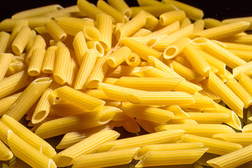 Heap of macaroni noodles reflecting on black background