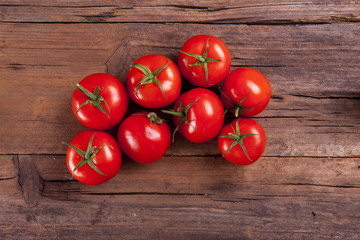 Bunch of tomatoes on vine shot from above on a wooden background