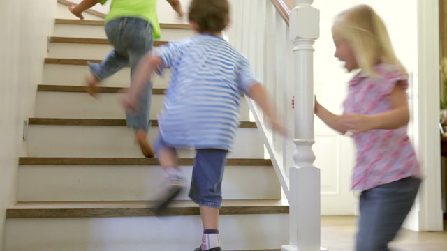 Group Of Children At Home Running Up And Down Stairs